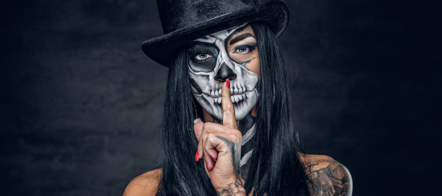 Female in Halloween silence. A woman in top hat and skull make up.