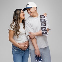 studio-maternity-monrovia Expecting couple holding ultrasound photos and baby shoes during a modern maternity photoshoot at a Monrovia photography studio