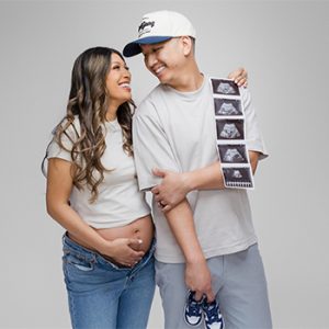 Expecting couple holding ultrasound photos and baby shoes during a modern maternity photoshoot at a Monrovia photography studio